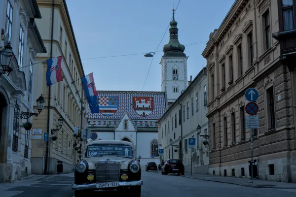 Auto d'epoca e Chiesa di San Marco a Zagabria con bandiere croate alla luce serale.