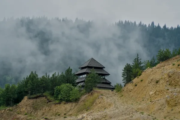 Casa simile a una pagoda su una collina sopra il lago Zaovine nel Parco Nazionale di Tara, circondata da pini e nebbia.