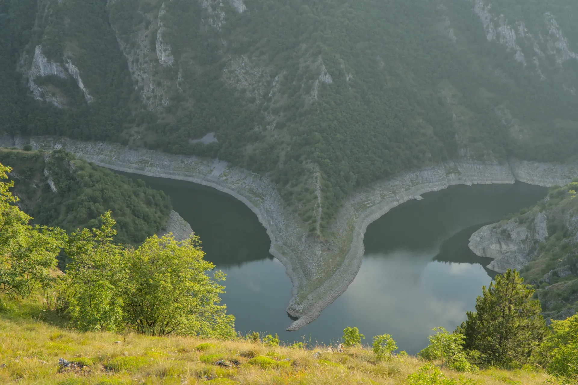 Meanders of the Uvac River in Serbia at sunset, surrounded by forested hills.