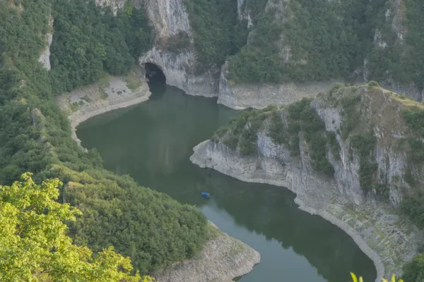 Il Canyon di Uvac in Serbia mostra anse tortuose del fiume e la Grotta di Ušačka, con una piccola barca blu nell'acqua.