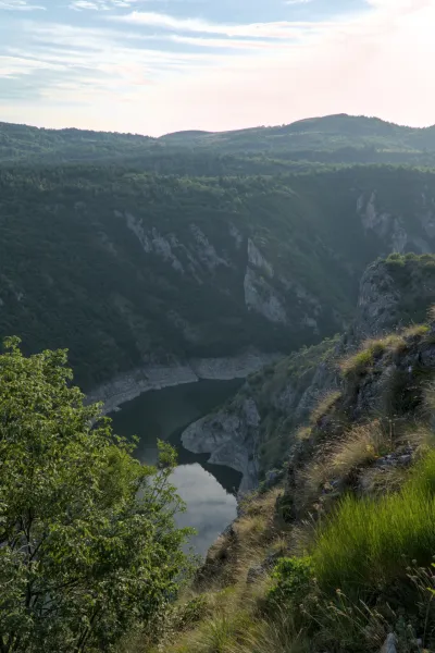 Le gole dell'Uvac al tramonto con un fiume calmo e montagne.