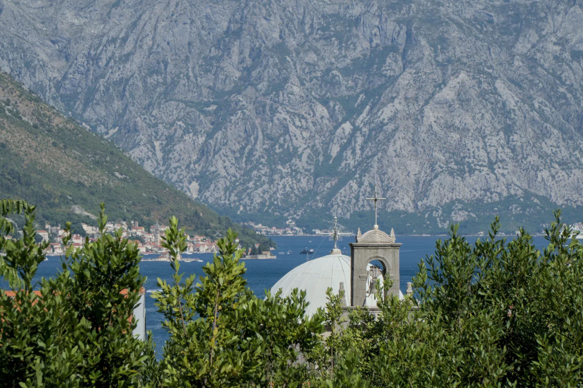 Die Kirche und die Bucht von Kotor in der Nähe von Morini, Montenegro, mit dramatischen Bergen im Hintergrund.
