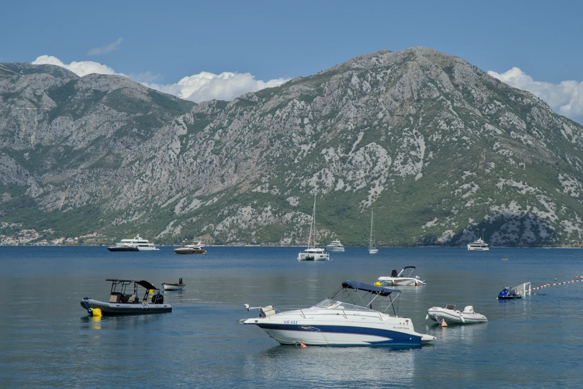 Verschiedene Boote und Yachten im Wasser vor einer Berglandschaft in der Bucht von Kotor.