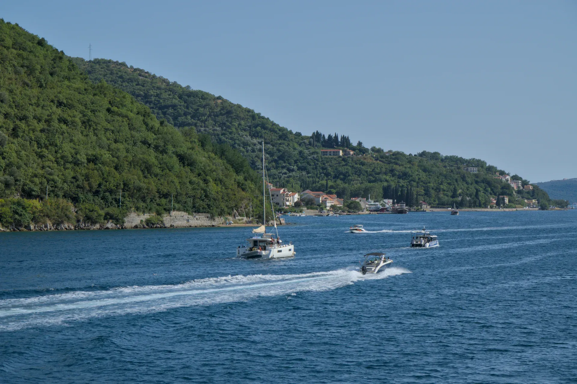 Boats in Kotor Bay, Montenegro, with green hills in the background, blue water photography for interior design.