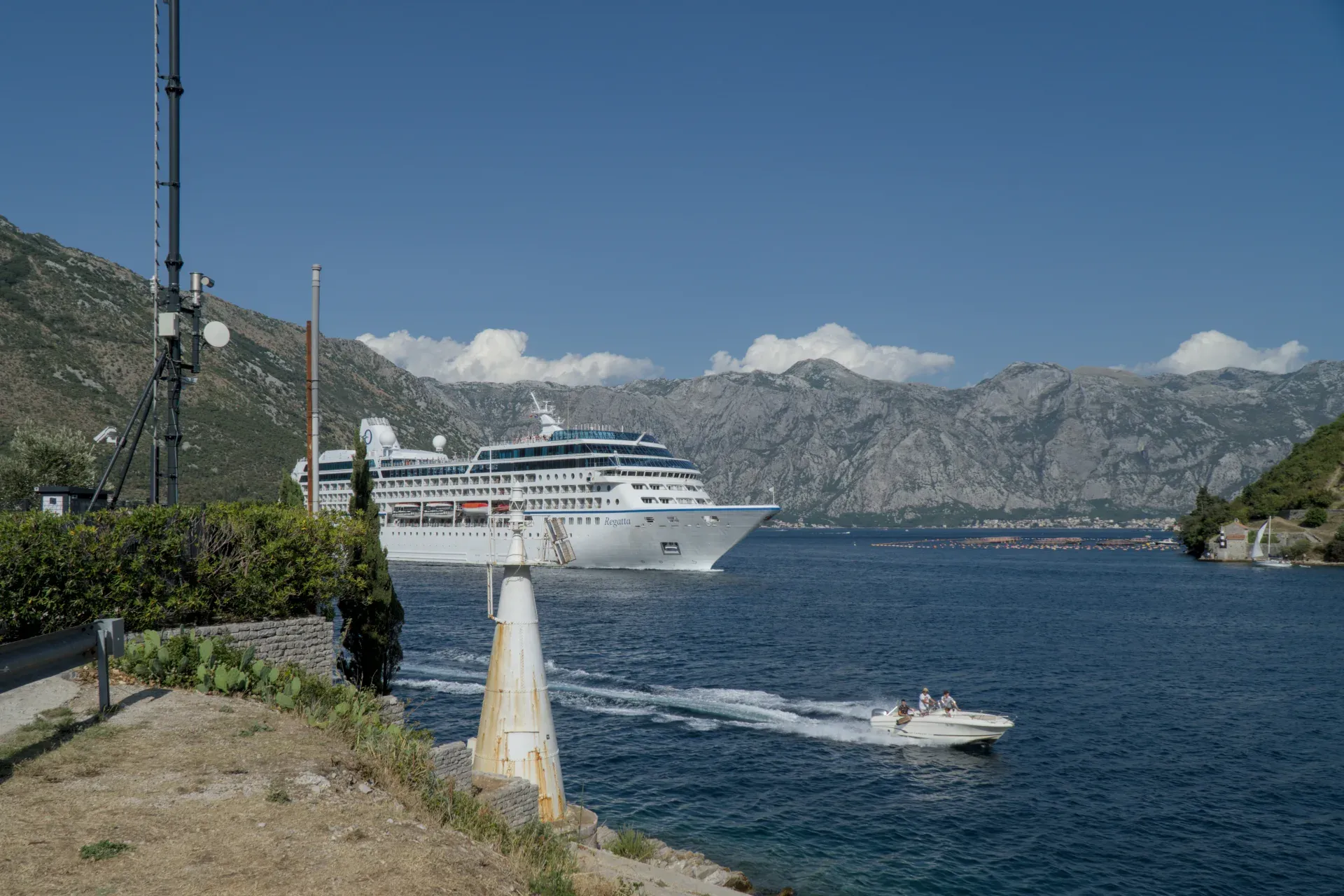 Un grand bateau de croisière quitte la baie de Kotor, Monténégro, avec de petits bateaux au premier plan.