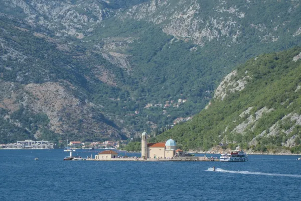 Vista della chiesa dell'isola Gospa od Škrpjela a Kotor, Montenegro, con montagne e mare.