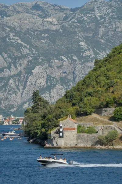 Svetionik na obali Kotorskog zaliva, Crna Gora, sa čamcem na vodi.