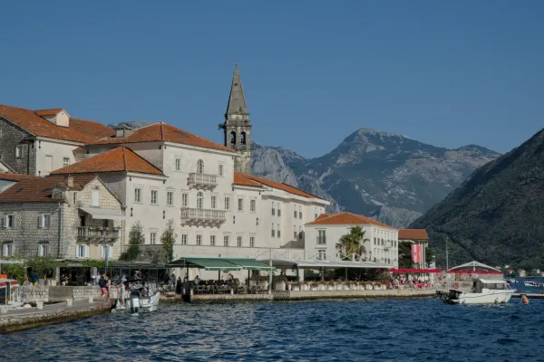 Atardecer en Perast, Montenegro, con luz dorada sobre edificios históricos y montañas al fondo.