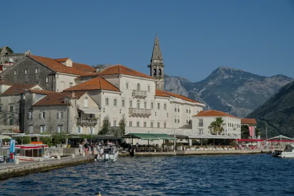 Vista de Perast en Montenegro al atardecer con edificios históricos y montañas al fondo.