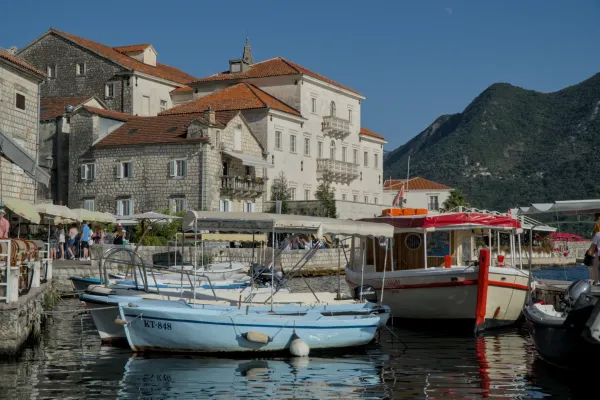 Čamac ispred istorijske arhitekture u Perastu, Crna Gora, po sunčanom danu.