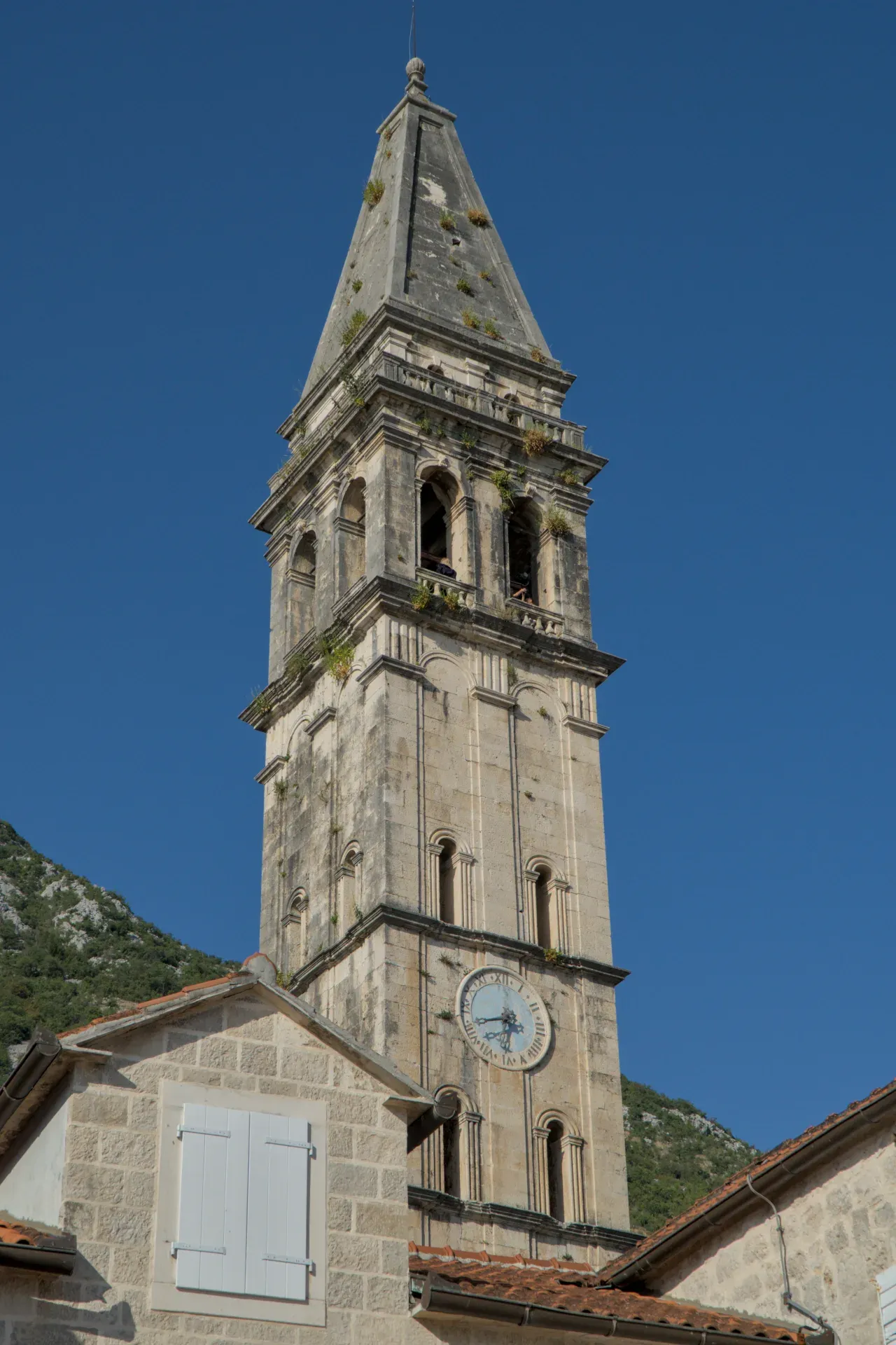 Ein detailreiches Porträt des alten Steinglockenturms von Perast, Montenegro, bei Abenddämmerung.