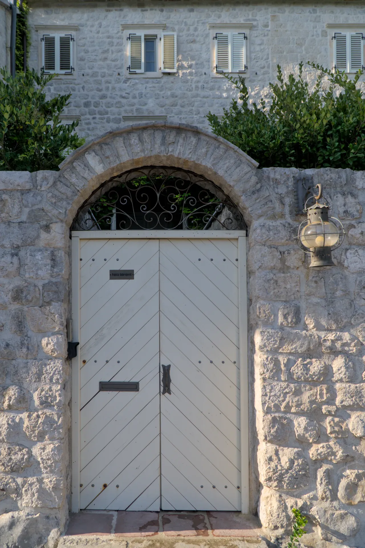Porta a Perast, Montenegro, con lampada ornata e architettura in pietra.