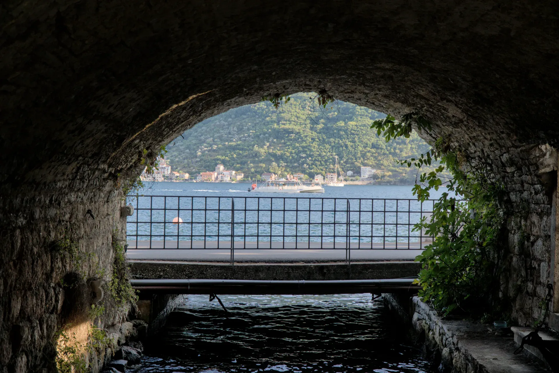 Meerblick mit Boot und Architektur durch eine steinerne Bogenpassage in Perast, Kotor.