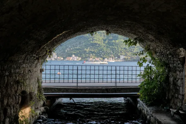 Meerblick mit Boot und Architektur durch eine steinerne Bogenpassage in Perast, Kotor.