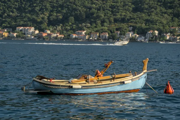 Ein helles, blaues Boot treibt auf dem ruhigen Wasser der Bucht von Kotor in der Nähe von Perast, Montenegro.