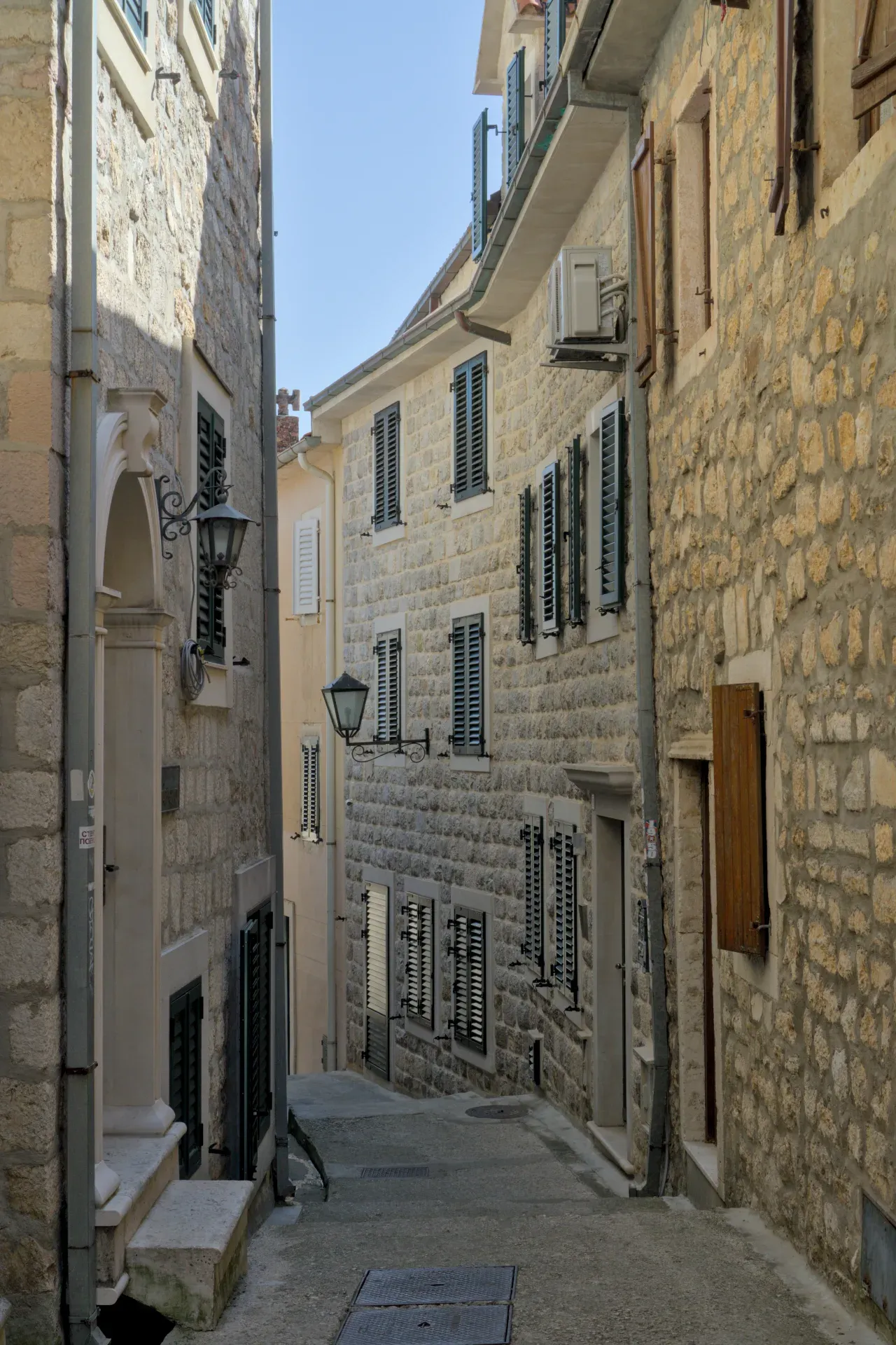 Un vicolo di pietra "улица старого города" a Herceg Novi, Montenegro, con persiane e lanterne tradizionali.
