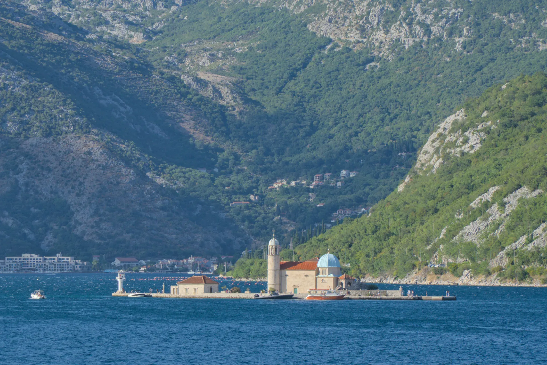 Die Inselkirche Gospa od Škrpjela auf dem Wasser vor bewaldeten Bergen in Kotor, Montenegro.