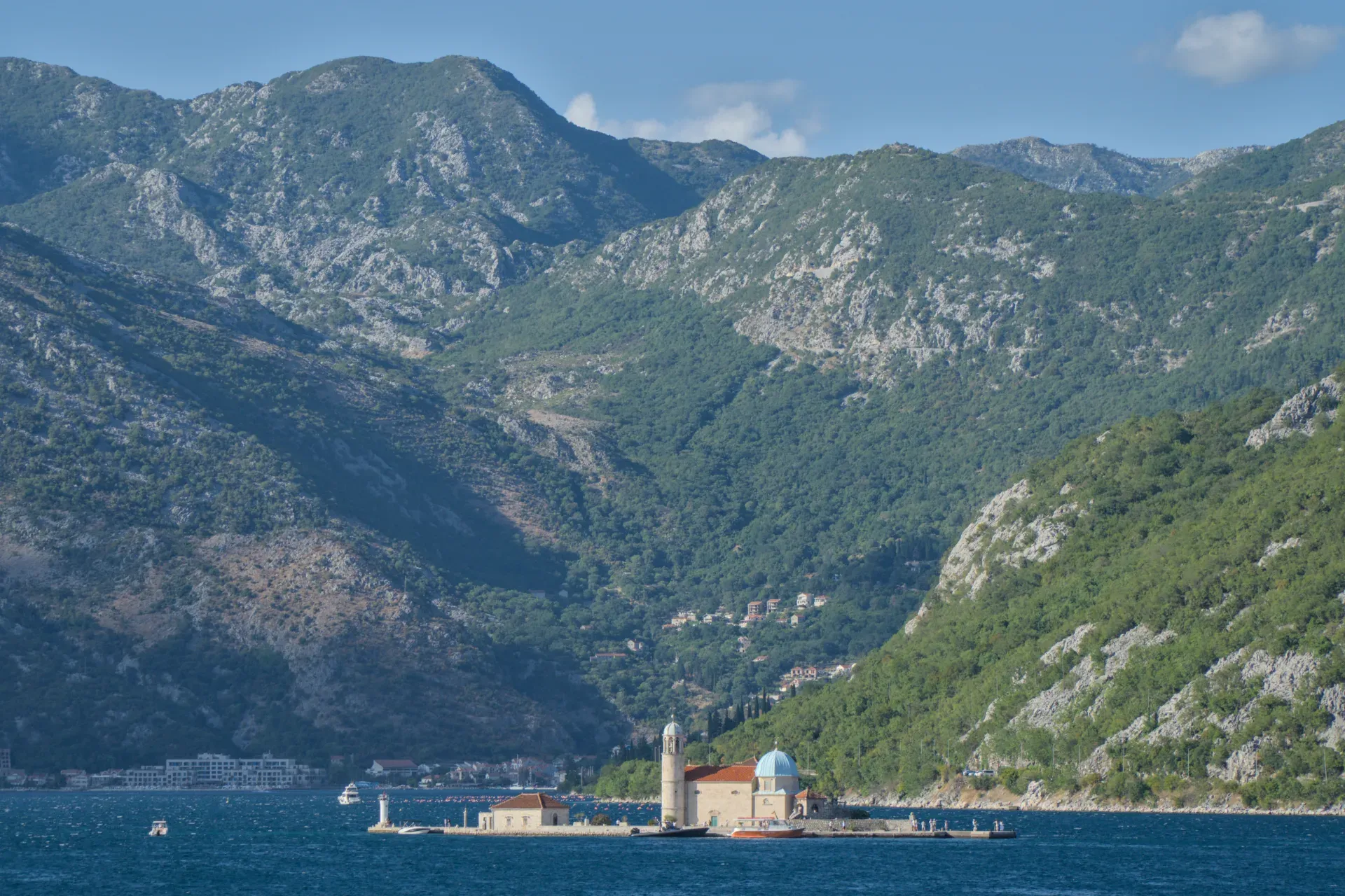 Die "Gospa od Škrpjela" Kirche auf einer Insel im Golf von Kotor, Montenegro, mit Bergen im Hintergrund.