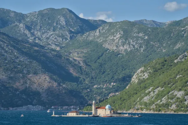 Die "Gospa od Škrpjela" Kirche auf einer Insel im Golf von Kotor, Montenegro, mit Bergen im Hintergrund.