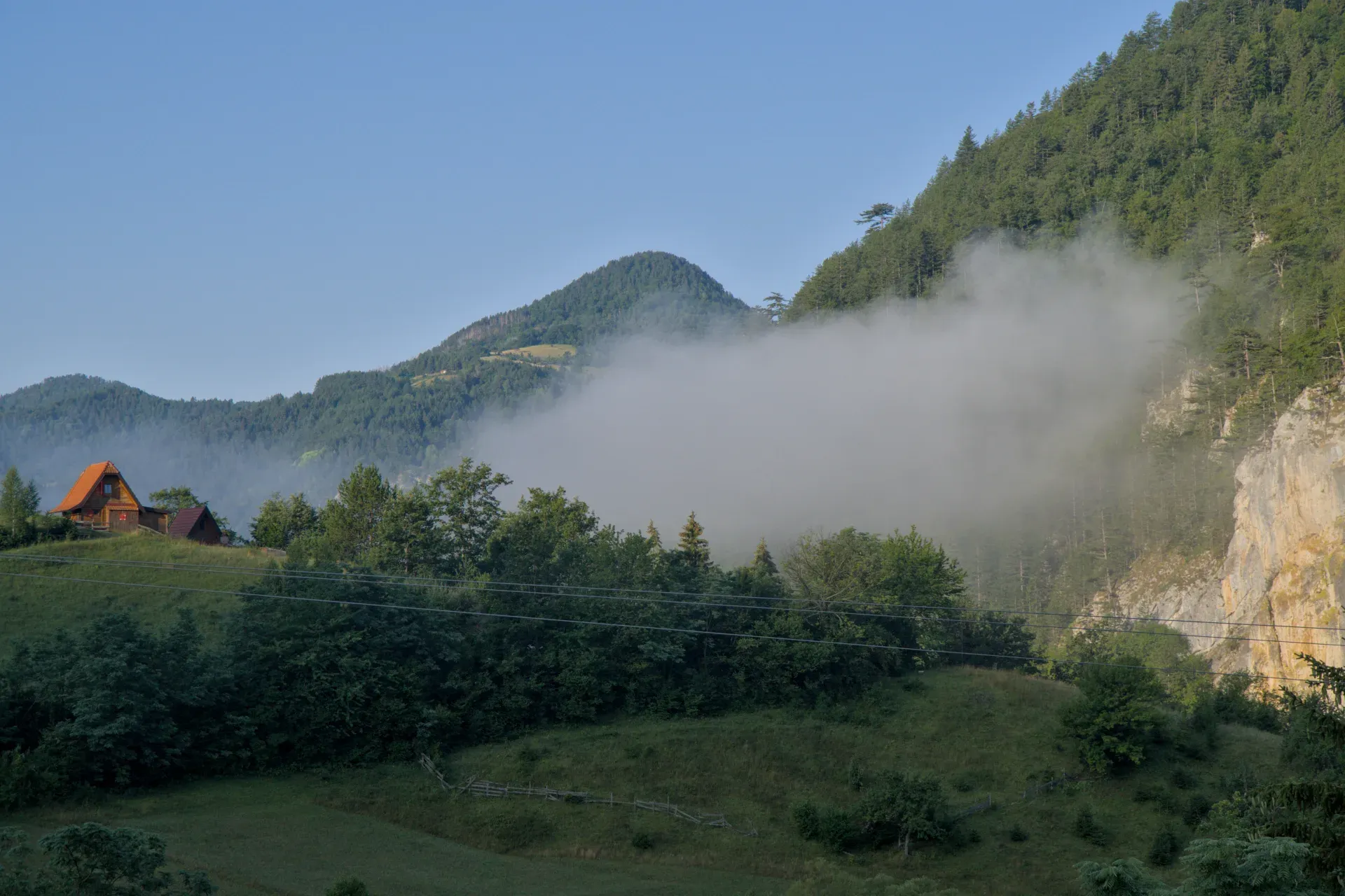 Brouillard matinal dans les montagnes de Zaovine, Serbie, avec des maisons et des forêts.