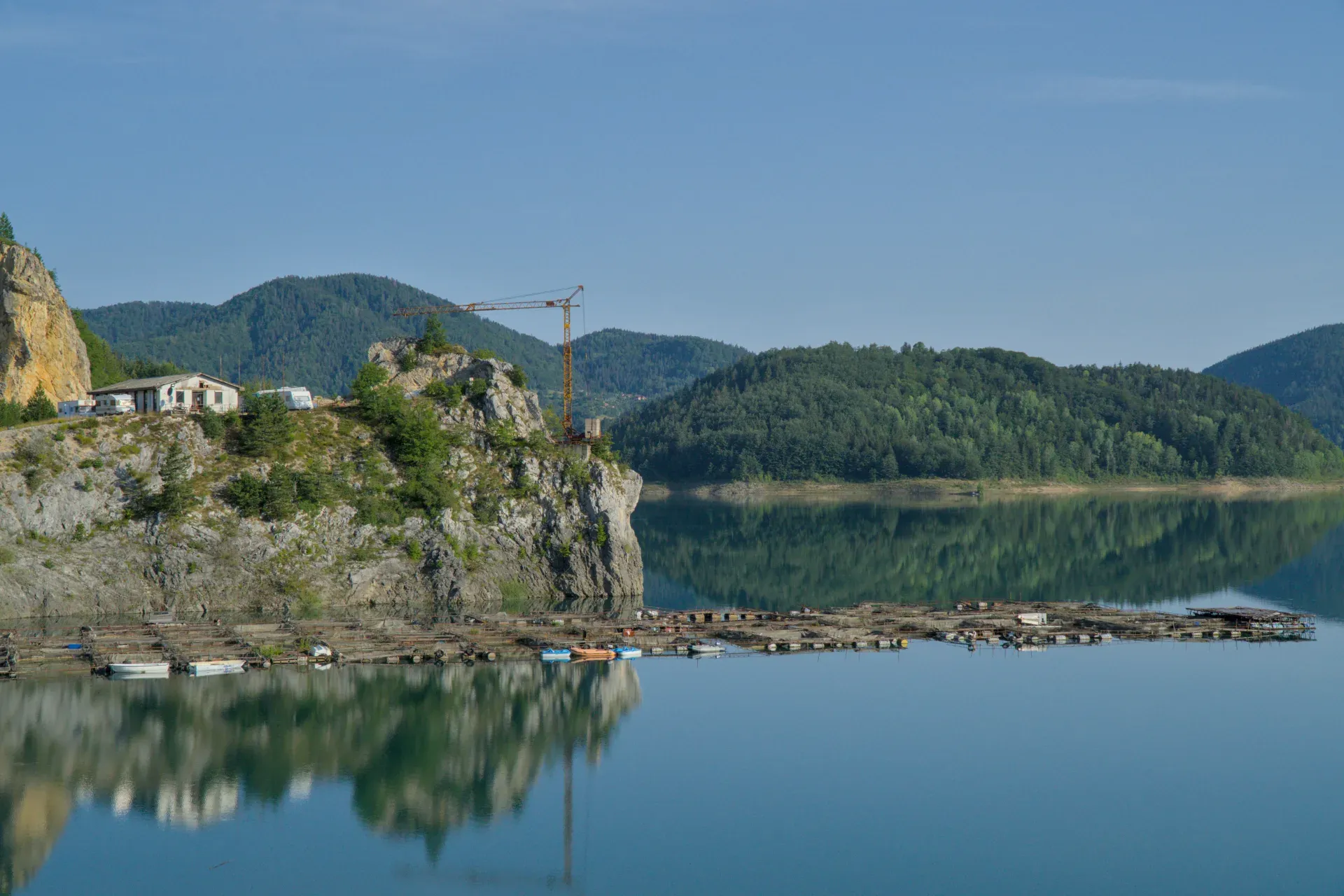 Lago Zaovine Serbia all'alba con acque calme che riflettono montagne verdi, ideale per decorazioni murali.