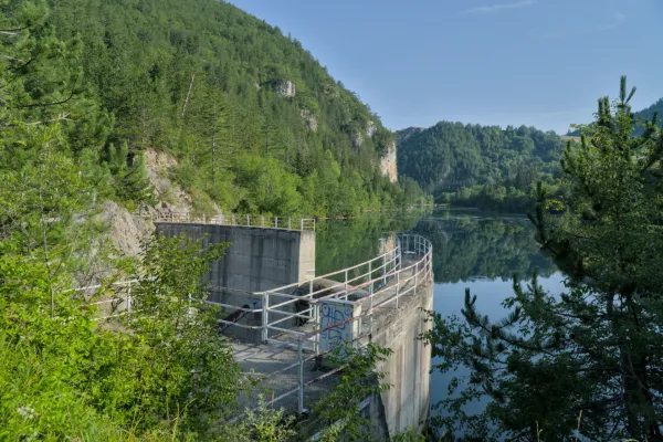 Barrage Lypovica à Zaovine, Parc National Tara, Serbie, avec des montagnes vertes à l'arrière-plan et des reflets dans l'eau.