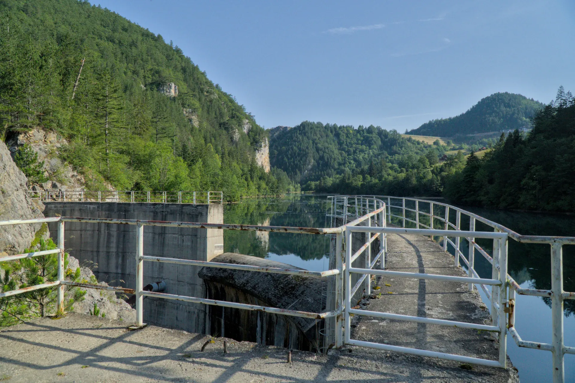 Der Spaiči-Staudamm in Zaovine, Serbien, mit umliegenden grünen Bergen und reflektierendem Wasser.