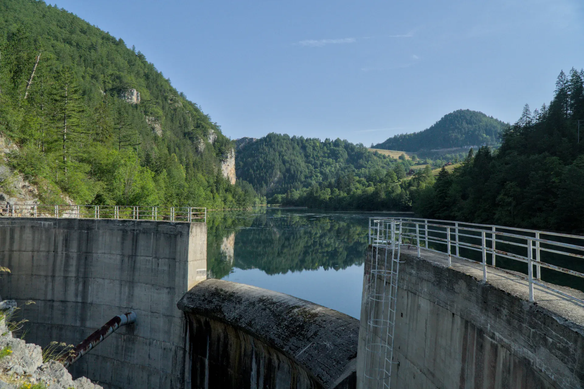 La Diga Spajići a Zaovine, Serbia, con uno sfondo montuoso e acqua riflettente, ideale per l'arte di galleria.