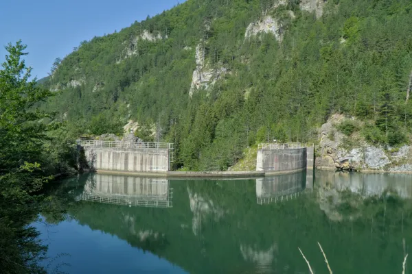 Spajići Damm bei Zaovine, umgeben von grünen Bergen und mit Spiegelung im Wasser.