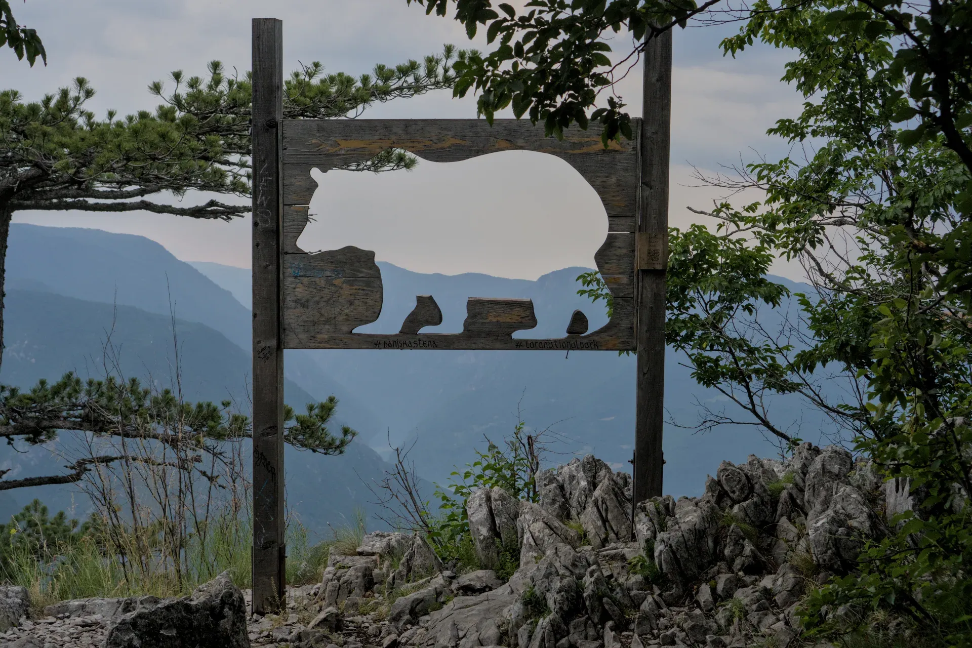 Holzskulptur eines Bären mit Blick auf die Berge im Nationalpark Tara, Serbien, bekannt als "Bansska Stena".