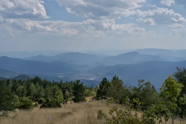 Vista di Višegrad dal Monte Janjač nel Parco Nazionale di Tara, Serbia, con montagne blu a strati e un cielo nuvoloso.
