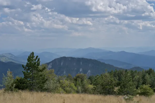 Vista accattivante dalla vetta di Janyač su montagne stratificate in Serbia, con sfumature serene di blu e verde.