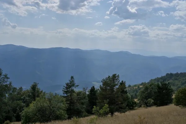 Vista de las montañas bosnias desde la cumbre de Yanach, con bosques exuberantes y colinas ondulantes en primer plano.