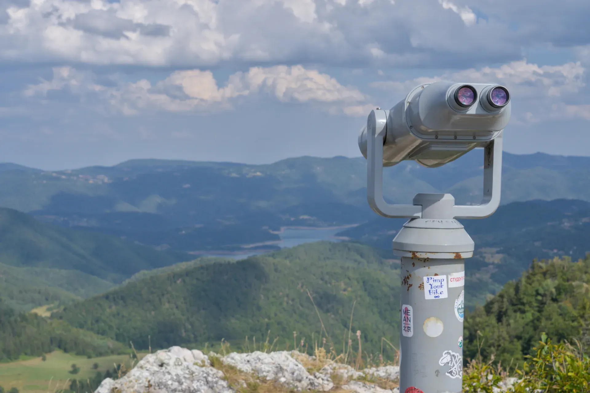 Ein Fernglas auf einer Bergspitze im Tara Nationalpark, Serbien, mit Blick auf weite Täler und Hügel.