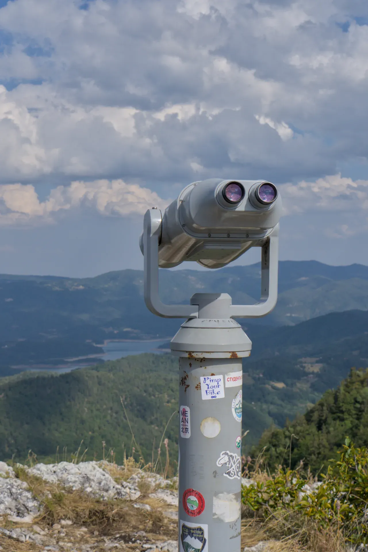 Un binocolo si erge su una cima montuosa affacciata su un paesaggio lussureggiante e collinare nel Parco Nazionale Tara, Serbia.