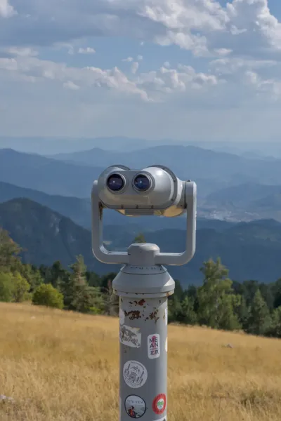 Un binocolo su una montagna che domina vaste catene blu e la città di Vyšehrad.