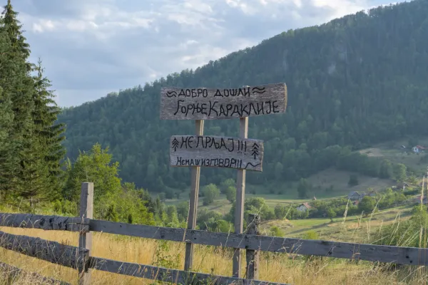 Un cartello serbo divertente con scritte dipinte a mano a Gornje Karajlić, Parco Nazionale di Tara, Serbia, sullo sfondo di montagne.