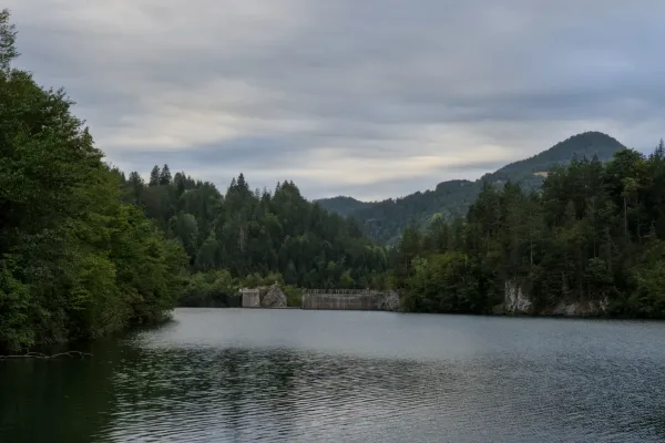Una diga sul Lago Spajići nel Parco Nazionale di Tara, Serbia, con colline boschi sullo sfondo.