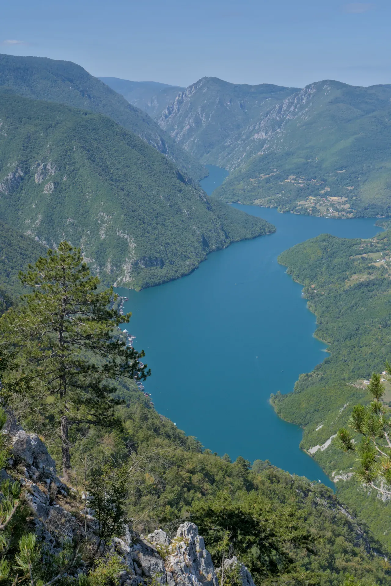 Il Lago Perucac visto dalla cima di Banjska Stena nel Parco Nazionale di Tara in Serbia, con acque turchesi e montagne verdi.