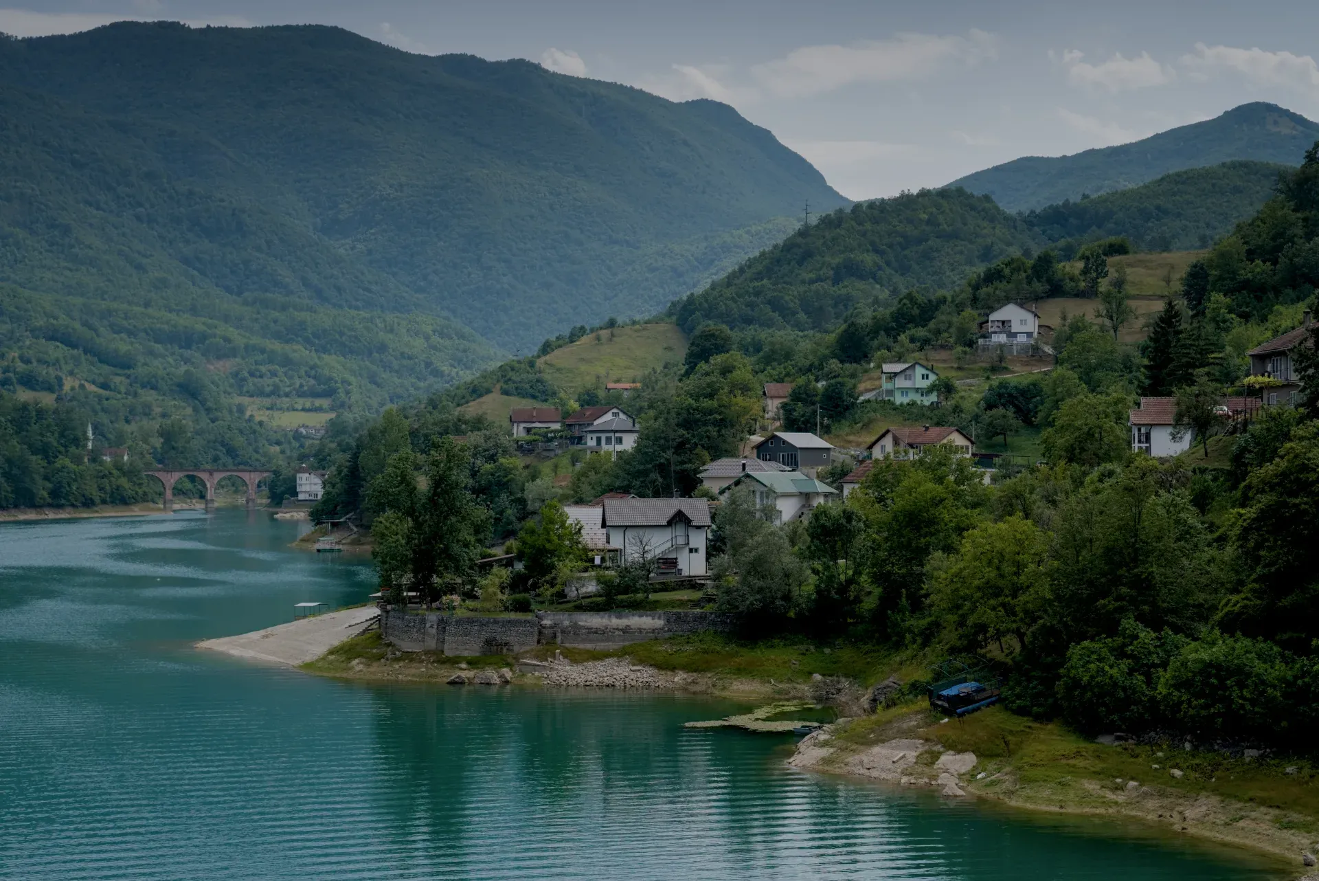 Paesaggio suggestivo con lago turchese e case in collina sulla strada per Mostar.
