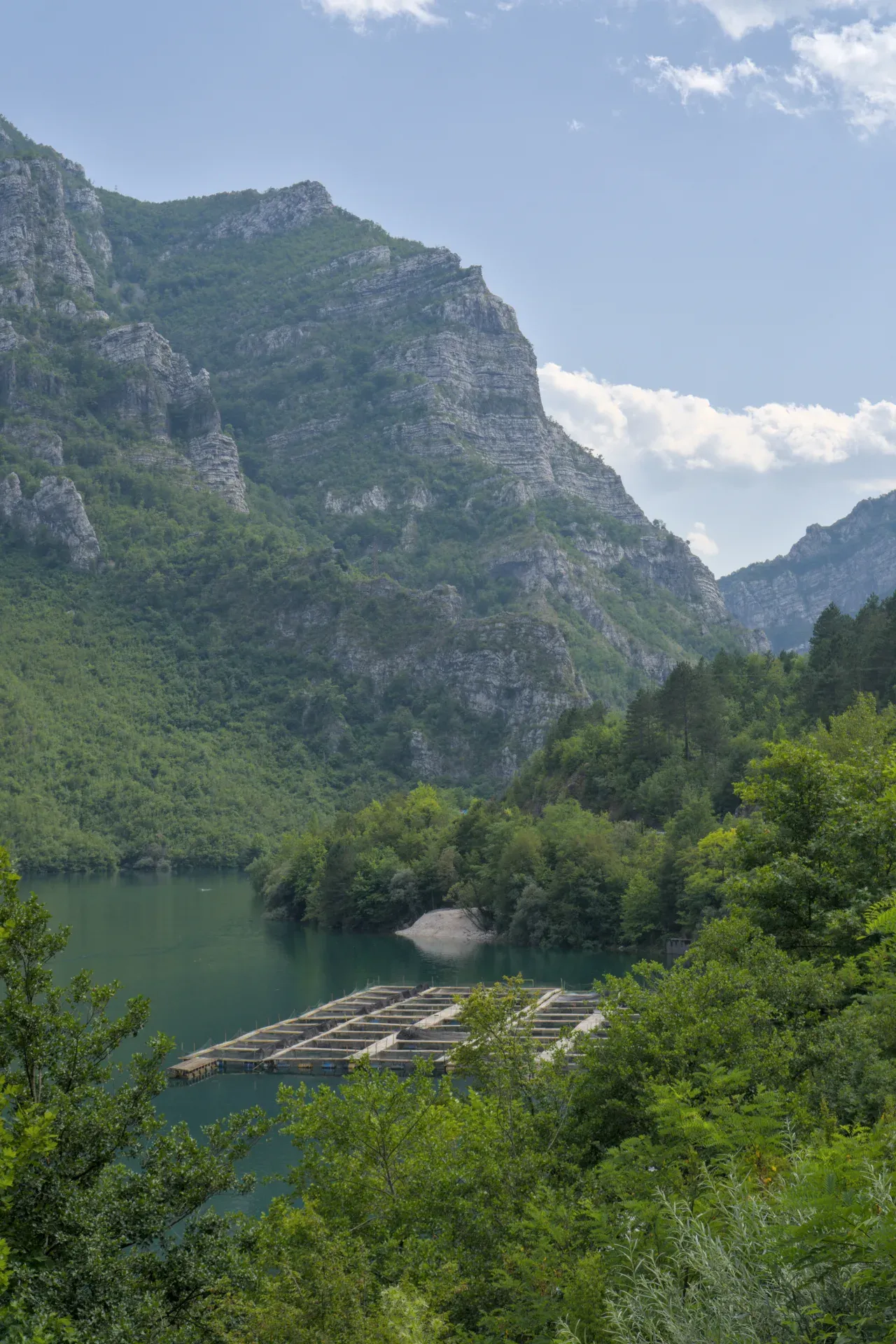 See mit Fischfarm vor majestätischen Bergen, aufgenommen auf der Route von Sarajevo nach Mostar.