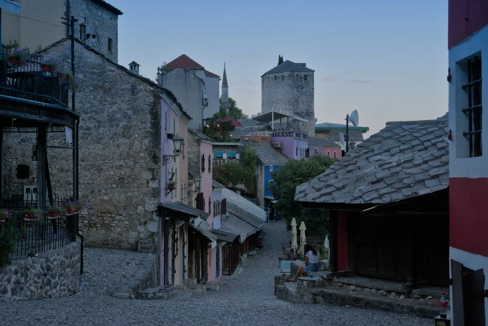 Calle empedrada en el Casco Antiguo de Mostar durante el predarassvetny chas, con edificios históricos en suave crepúsculo.
