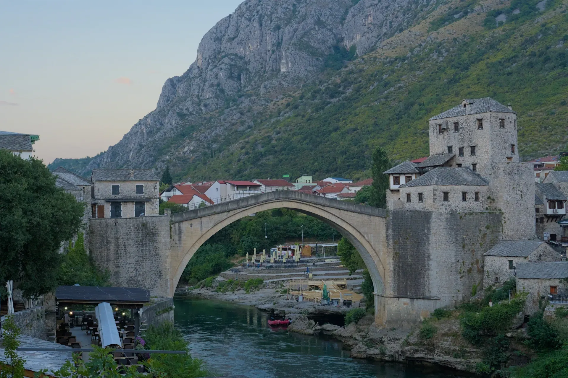 Le vieux pont Stari Most à Mostar, Bosnie-Herzégovine, capturé dans la douce lumière de l'aube avec un arrière-plan de rivière et de montagne.
