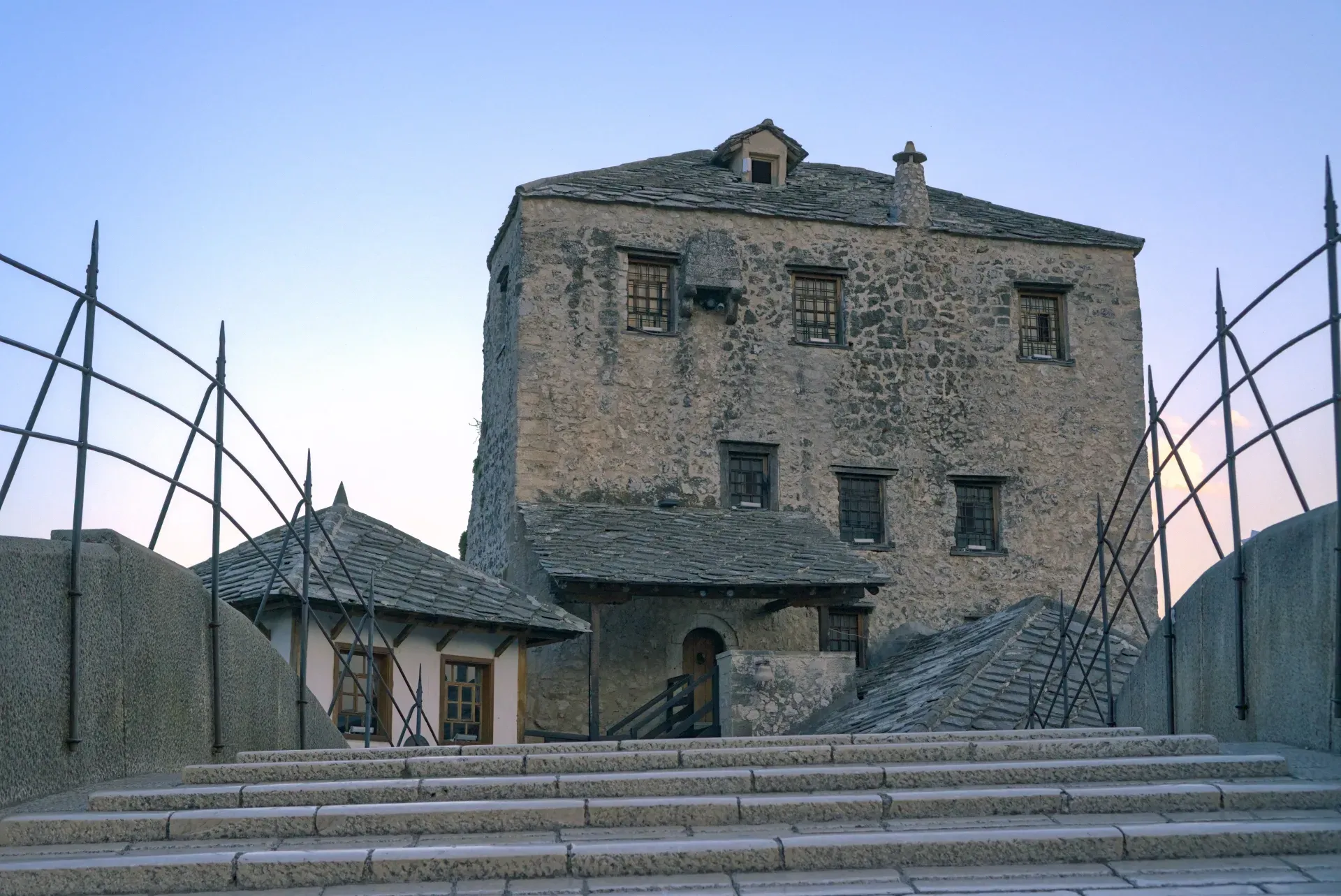 Un'antica torre di pietra e edifici adiacenti vicino al Ponte Vecchio a Mostar, Bosnia ed Erzegovina, con gradini in pietra.