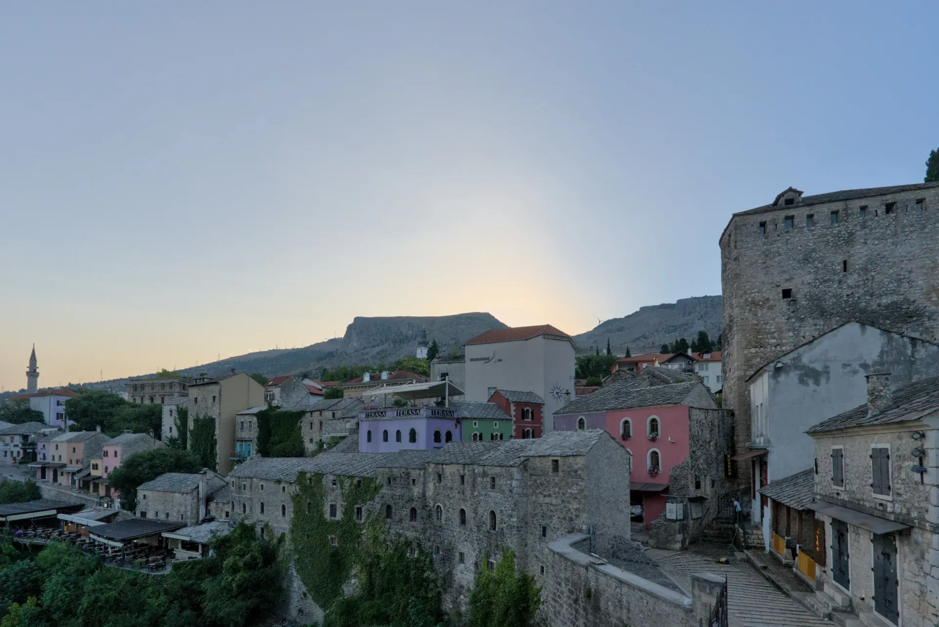 La storica Città Vecchia di Mostar si sveglia alla luce del mattino, "старый город просыпается", mostrando edifici in pietra.
