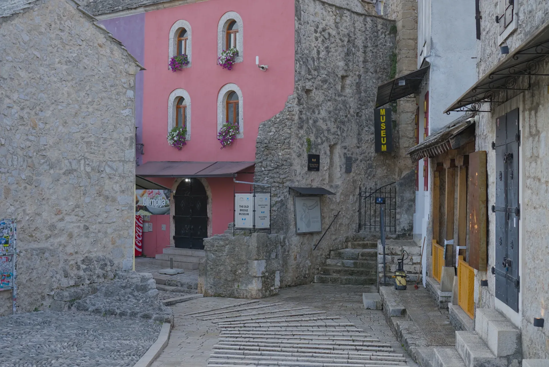 Calles vacías en el viejo Mostar al amanecer con edificios rosas y de piedra.
