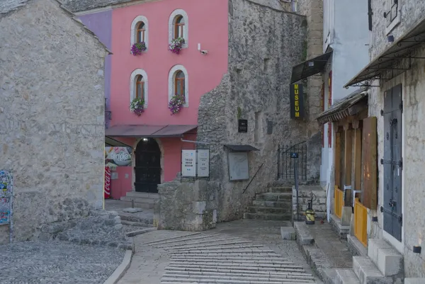 Calles vacías en el viejo Mostar al amanecer con edificios rosas y de piedra.