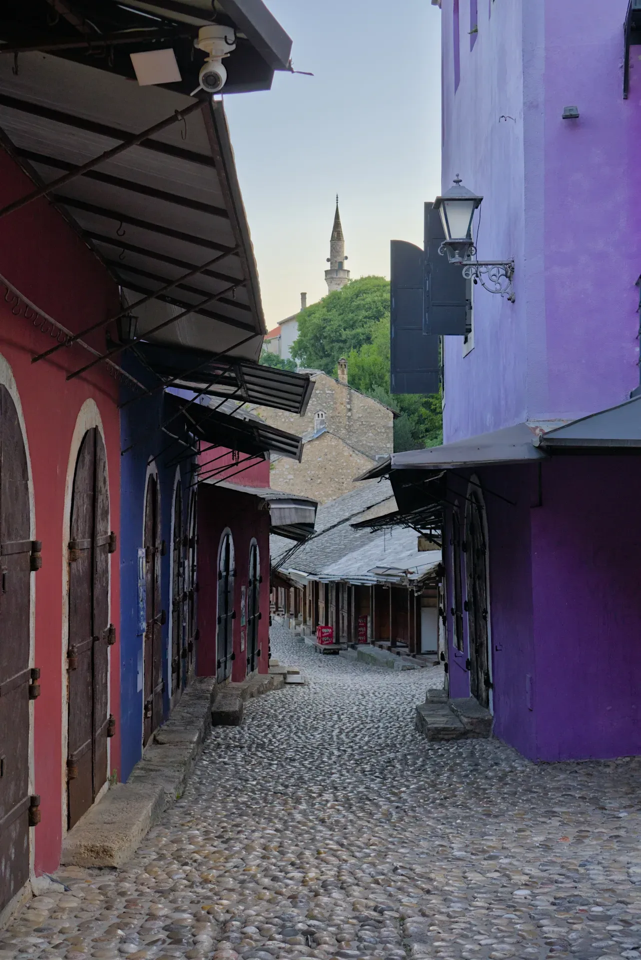 Mattina presto nella città vecchia di Mostar, con facciate vivaci e un sentiero acciottolato.