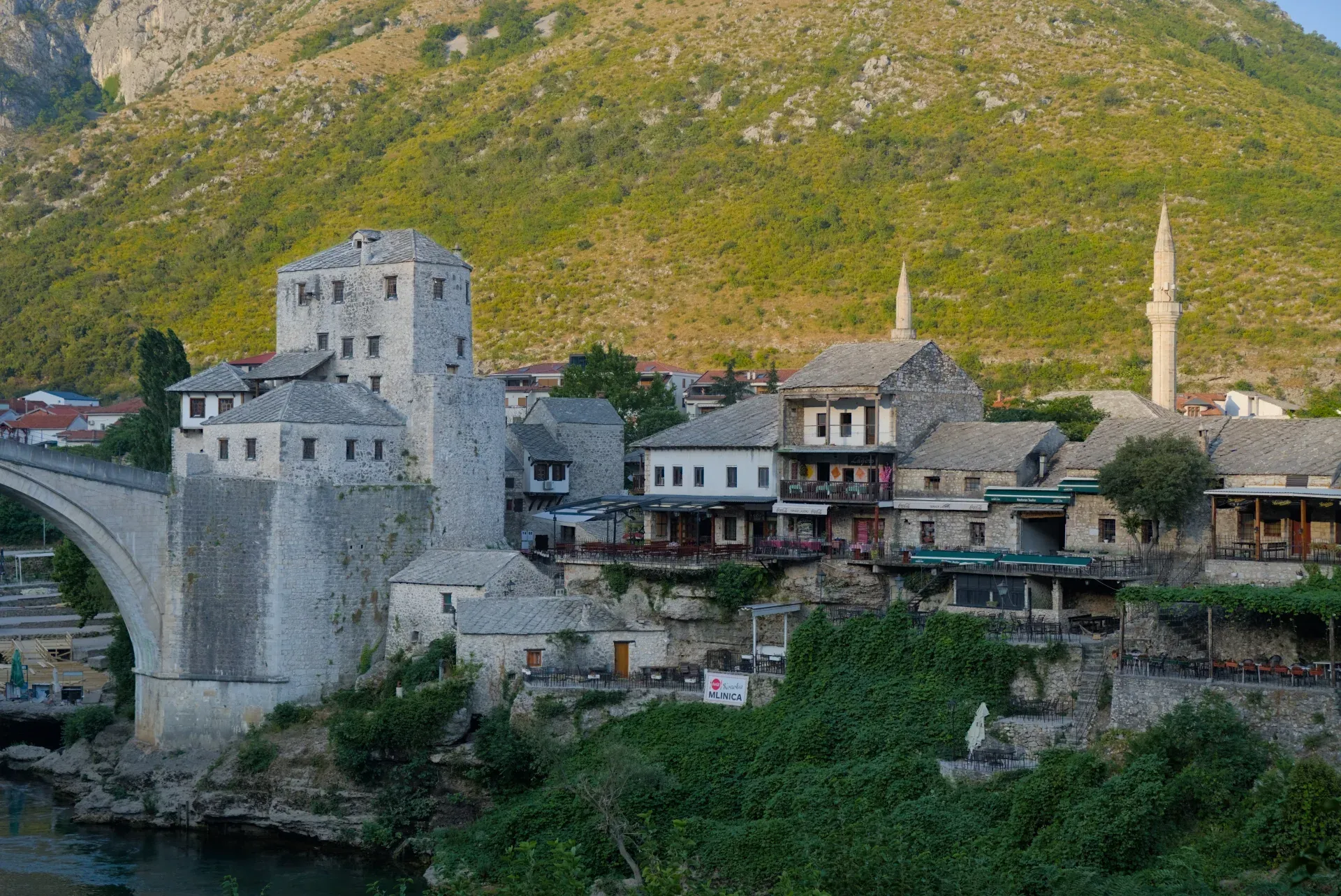 Il vecchio Mostar nella luce dorata dell'alba, con il suo storico ponte in pietra e gli edifici circostanti.