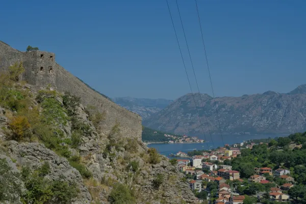 Blick von der Festungsmauer in Kotor auf Dobrota und Prčanj, mit Bergen und Meer im Hintergrund.